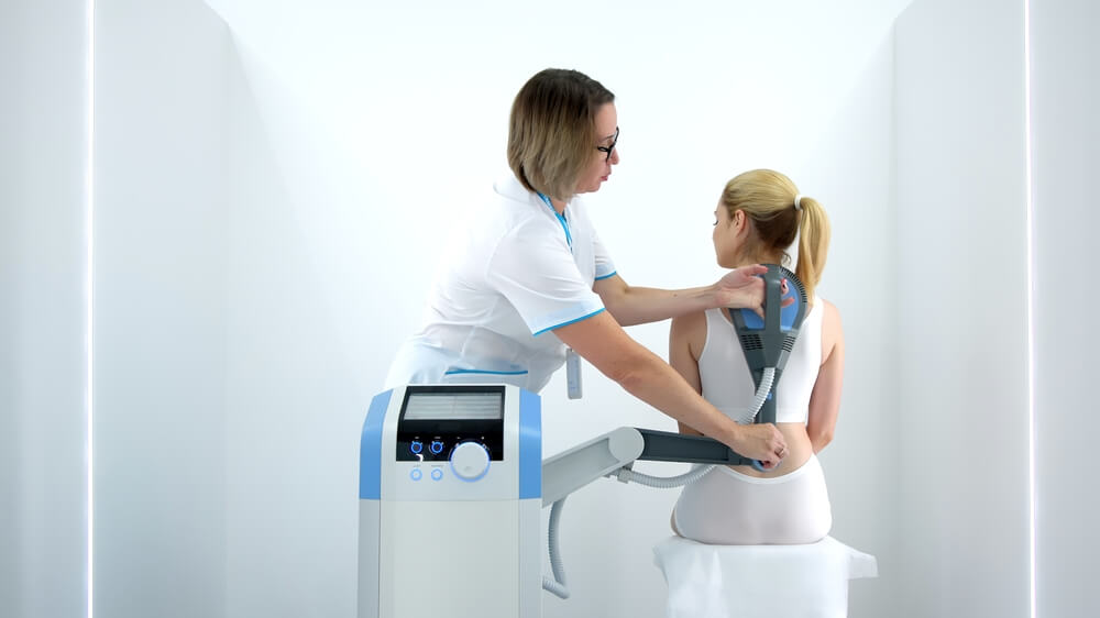 A physiotherapist administers advanced electromagnetic therapy for back pain relief using state-of-the-art equipment. Ideal for showcasing effective pain management and rehabilitation techniques.
